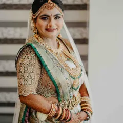 A portrait of our stunning bride wearing a custom-designed blouse with her white and green silk saree. The intricate floral embroidery on the blouse sleeves is a work of art, perfectly complementing her traditional gold jewelry.