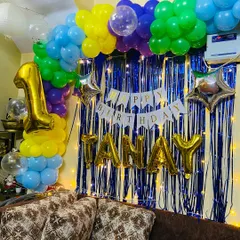 This image shows the complete setup for Tanay's first birthday, including the large '1' foil balloon, the name in gold letters, and the 'Happy Birthday' banner.