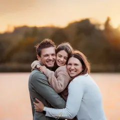 A beautiful, tight family hug against the warm glow of a sunset over the water. These are the simple, authentic moments of connection that I strive to capture in every family photography session.