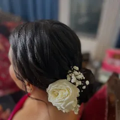 A side view of the classic floral bun, showing how the white rose is neatly tucked into the side. This style is perfect for pairing with a silk saree.
