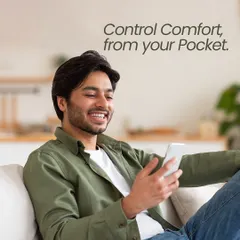 Control comfort from your pocket. This image captures the pure satisfaction of managing your home's environment effortlessly from your smartphone while relaxing on the couch.