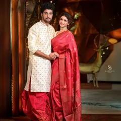 A classic and elegant couple portrait. The subjects are dressed in traditional Bengali attire, and the formal pose captures a sense of grace and togetherness, perfect for a wedding album.