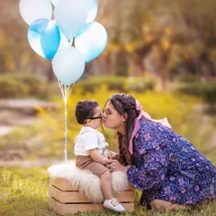 A sweet kiss from mom during an outdoor family shoot. The soft, natural light and beautiful greenery create a warm and loving atmosphere.