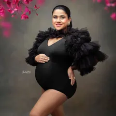 This mama is absolutely glowing in a bold black bodysuit with dramatic ruffled sleeves. Paired with a floral frame, it creates a modern and high-fashion maternity look.