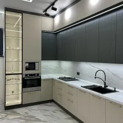 A closer look at a two-tone kitchen design, featuring textured dark upper cabinets and smooth beige lower cabinets, complemented by a white marble backsplash.