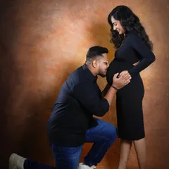 A classic and heartfelt pose where the father-to-be kneels to kiss the baby bump. It's a beautiful way to show his connection and love for their coming child.