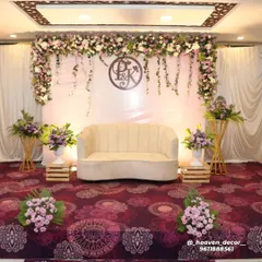 A full view of our personalized engagement stage, featuring the couple's monogram. The clean white backdrop is framed by a garland of pastel flowers and trailing ivy, creating a soft and romantic ambiance.