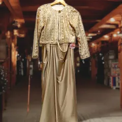 An exquisitely beautiful gold drape skirt paired with a stunningly embroidered jacket. This ensemble radiates elegance and is perfect for a wedding reception or a glamorous party.