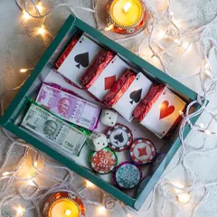 Here's a closer look inside the edible Poker Set hamper. You'll find chocolate currency notes, dice, and delicious brownie playing cards, making it a standout gift for any card party host.