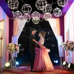 A posed portrait of the couple at their sangeet entrance. The beautiful decor, with its warm lights and floral arrangements, creates a perfect backdrop for a romantic photo.