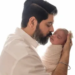 A father's gentle kiss on his newborn baby's forehead. A simple, powerful portrait showing the instant bond and love.