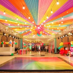 A rainbow of fun! The ceiling of this hall was transformed with vibrant, multi-colored drapes and string lights for a Trolls-themed birthday party, creating a festive canopy over the entire celebration.