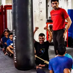 A moment of victory and encouragement during a group session. A coach looks on as a member celebrates after completing a tough drill on the heavy bag. This is the supportive atmosphere we cultivate.