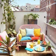 A concept for a bright and cheerful balcony, using colorful cushions on wicker furniture and plenty of potted plants to create a vibrant, cozy corner for relaxing.