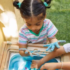 A child completely absorbed in the tactile sensation of sensory materials. This kind of focused play helps build concentration and allows children to learn about the world through their hands.