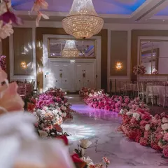 I can create a magical entrance for the bride. This walkway is lined with beautiful pink and white flower arrangements on the floor, leading to a grand hall.