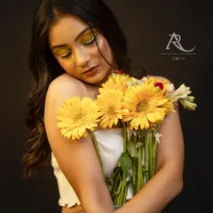 In the same series, this softer pose shows a different side of the model's range. The gentle embrace of the flowers and the downward gaze create a more romantic and introspective mood, demonstrating versatility within a single shoot.