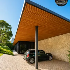 We designed this modern carport to feel both open and protective. The cantilevered roof with its rich wood-panelled ceiling is supported by a single, sleek pillar, creating an unobstructed, minimalist look that perfectly complements the home's architecture while providing excellent vehicle protection.