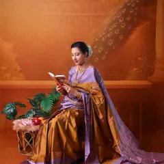 A portrait that combines tradition with a love for knowledge. The mom-to-be reads a book, seated gracefully in her saree against a painted backdrop of a classic Indian palace.