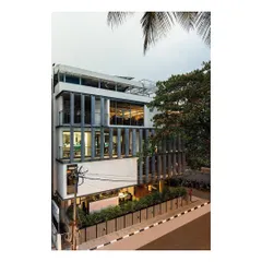 The Slate House seen from the street, showing the layering of its facade. The design uses post-tensioned slabs to achieve column-free interior spaces, while the exterior is articulated with ultra-high-performance concrete fins that provide shade and visual rhythm.