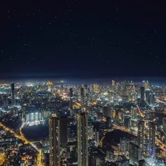 A stunning aerial view of Mumbai at night, where the city's dense network of lights shines brightly under a sky filled with stars.