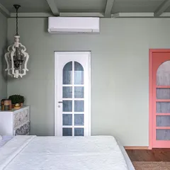 We used color to create distinct zones in this master suite. The main bedroom is painted in a calming sage green, a peaceful backdrop for the intricately carved white furniture. A playful peach door opens into a vibrant walk-in closet, creating a delightful contrast and a little pocket of surprise.