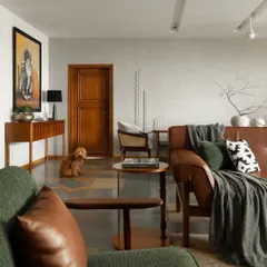 This living room blends modern comfort with Indian heritage. The flooring is a detailed pattern of Kota stone and Jaisalmer marble, while the furniture combines clean lines with warm materials like leather and dark wood.