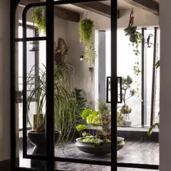 The view into the 'Sun Room' through custom arched doors. This space was designed to be a peaceful escape, a garden in the sky filled with hanging plants, a lotus pond, and curated botanical arrangements.