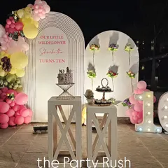 This "little wildflower" theme for Sharbodita's 10th birthday is both sweet and sophisticated. The setup features clean white backdrops, a beautiful pink and yellow balloon arch, and marquee numbers, creating a lovely nighttime celebration.