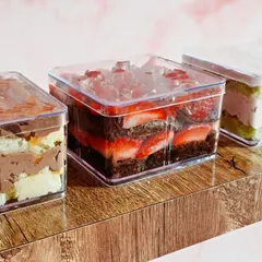 A lineup of my popular tub cakes. These clear boxes show off the beautiful layers of cake, cream, and fruit, featuring flavors like Chocolate Strawberry and Rose Pistachio.