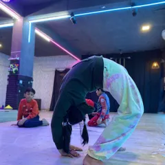 A young gymnast holds a strong backbend position on the floor. This exercise is crucial for developing spinal flexibility and shoulder strength needed for tumbling and acrobatics.