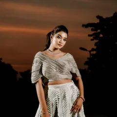 A dramatic bridal portrait set against a sunset sky. The lighting emphasizes the bride's stunning outfit and creates a powerful, moody atmosphere.