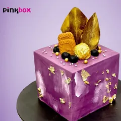We were asked to create something "out of the box," so we made this purple cube cake. It's an abstract, modern design topped with Biscoff cookies and gold leaf for a truly unique celebration.