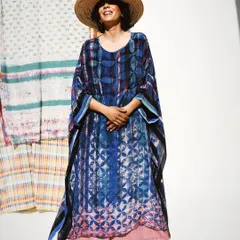 A joyful, full-length portrait for Wandering Silk. The model's smile and the flowing silhouette of the kaftan against a backdrop of printed textiles perfectly capture the brand's free-spirited and artistic vibe.