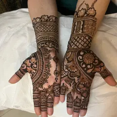 This designer mehndi plays with asymmetry. One hand has a dense floral pattern, while the other features a lighter, more open design with a central mandala, offering a unique and modern look.