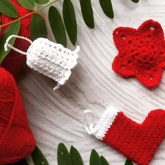 A flat-lay of our red and white Christmas ornaments. This set includes a crochet bell, a star, and a mini stocking, perfect for a cohesive color theme on your tree or as festive gift toppers.
