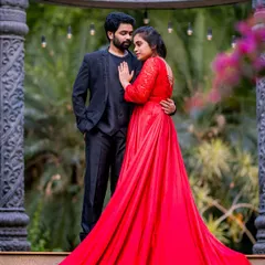 A dramatic and romantic pre-wedding photo. The couple's outfits, a vibrant red gown and an all-black suit, create a powerful look.
