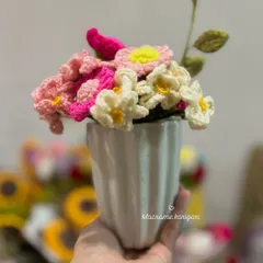 Holding a small vase of our handmade crochet daisies. These delicate flowers are perfect for a small desk or bedside table.