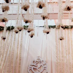 The decor of a daytime Odia wedding, featuring a Ganesha motif against a backdrop of white curtains and hanging floral arrangements. These details set the serene and sacred tone for the ceremony.