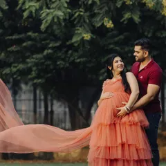 A beautiful, candid moment captured. The long, flowing train of the coral gown adds a touch of drama and elegance to this maternity photo.