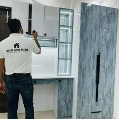 This custom unit combines a study desk, overhead cabinets, and a full-height wardrobe. The design uses a mix of white and a blue-textured laminate for a modern look.