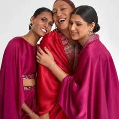 A moment of connection during the shoot. The makeup for all three women was designed to be harmonious yet individual, using radiant skin and defined features to complement the couture.