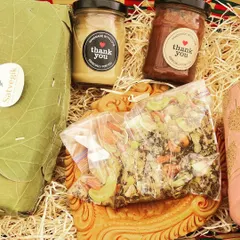 A close-up of my Diwali hamper, showcasing the eco-friendly packaging and the delicious treats inside. You can see the nut butters, trail mix, and a loaf of bread wrapped in a leaf.