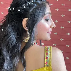 A side view of the pearl-studded hairstyle. The combination of the braid and soft waves creates a beautiful texture and finish.