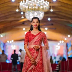 For this client attending her brother's engagement, we chose a sophisticated and elegant look. The makeup features a classic red lip and defined eyes, paired with soft, side-parted hair that beautifully complements her stunning red lehenga.