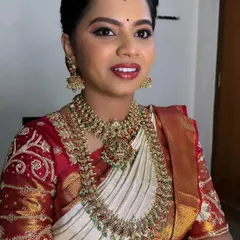 A close-up of Sahana's wedding day makeup. The look is classic and timeless, with a focus on her eyes and a perfectly matched lip color for her red and white saree.