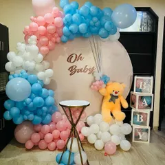This "Oh Baby" themed decoration is perfect for a baby shower or gender reveal party. It features a large circular backdrop with pink, blue, and white balloons, a cute teddy bear, and "BABY" display boxes. It’s a complete photo corner setup.