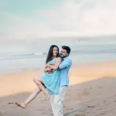 A fun and candid shot of a couple on the beach, with the groom playfully lifting the bride, capturing their joyful energy.