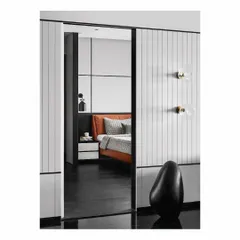 An inconspicuous door in the living room wall slides open to reveal the master bedroom. The design creates a seamless transition, with the stark black, white, and grey color palette of the bedroom offering a sophisticated contrast to the tan leather bed.