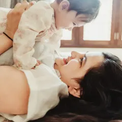 Another moment from a lifestyle session, showing a mother playfully lifting her baby in the air. The natural window light creates a soft and authentic feel for this family portrait.